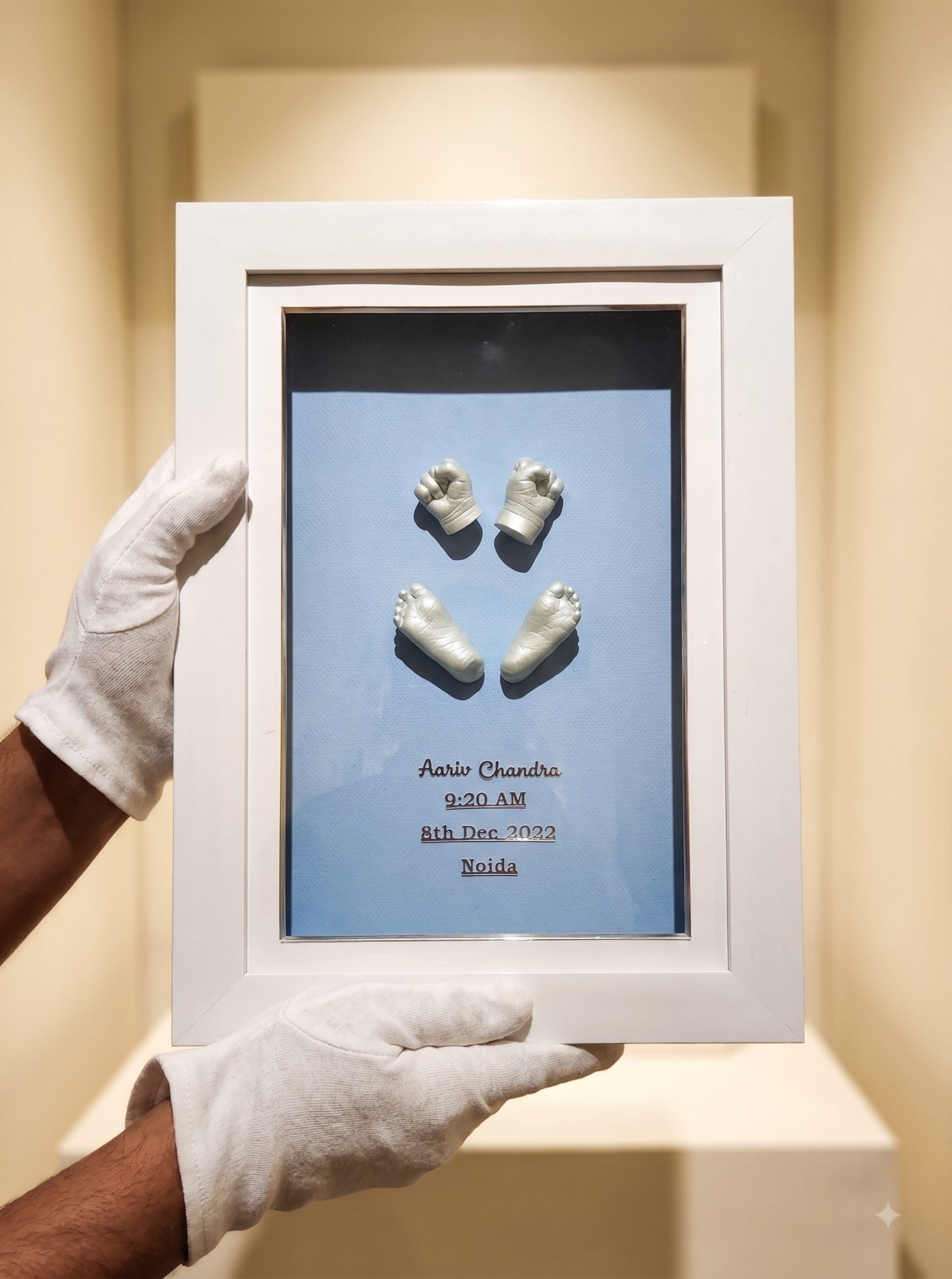 A pair of gold foot casts mounted in a white frame