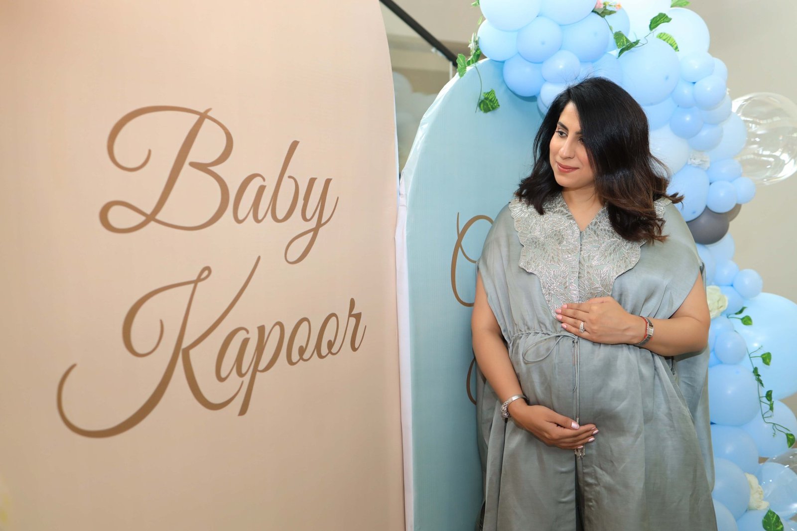 Mother-to-be photographed in front of the decorated backdrop