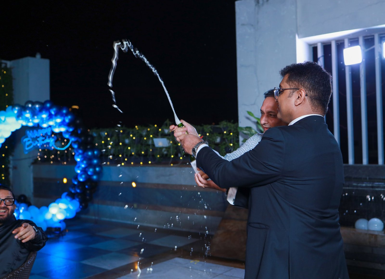 Guests opening a bottle to celebrate at an evening birthday party