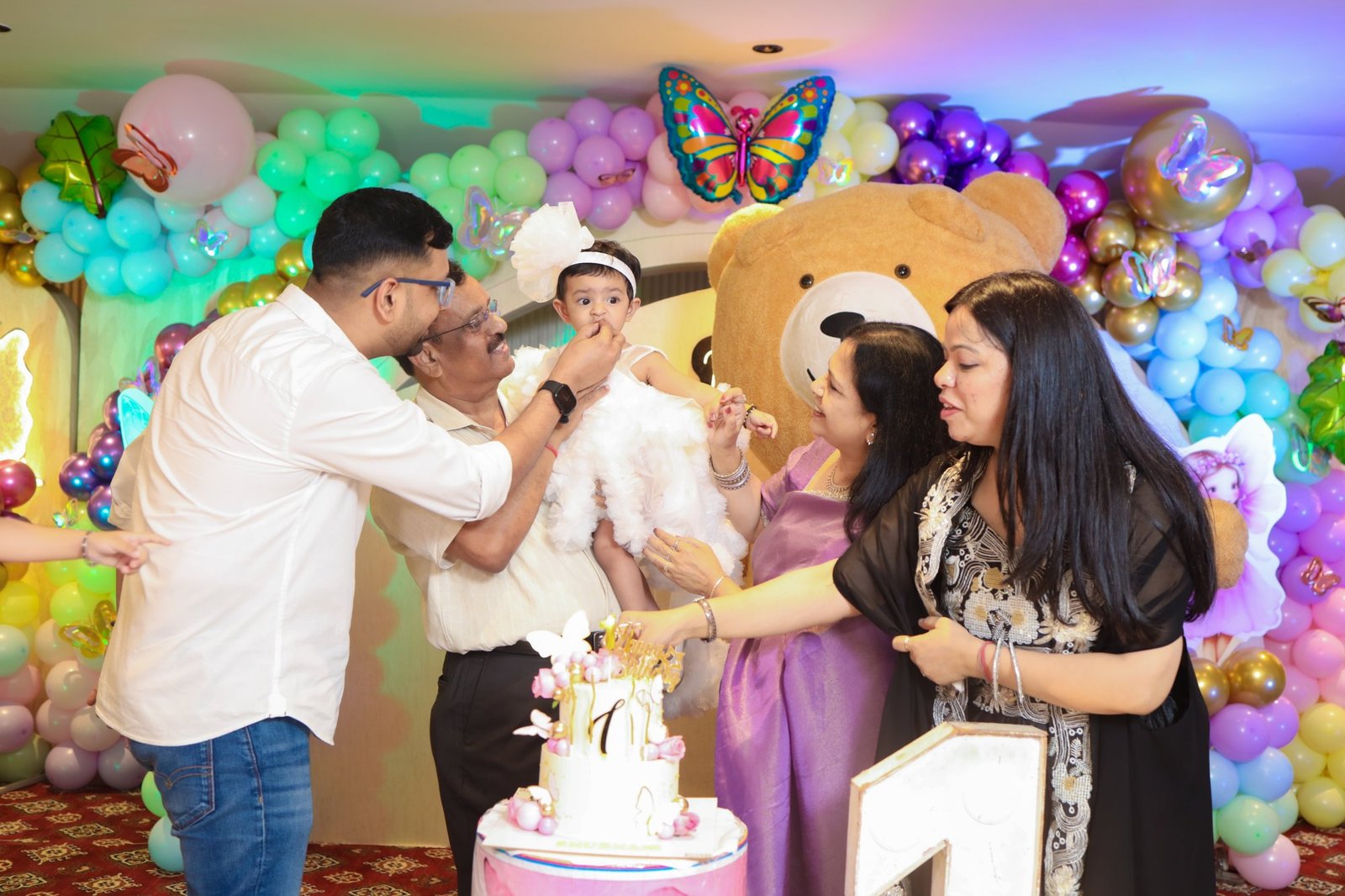 Parents helping their child cut the birthday cake