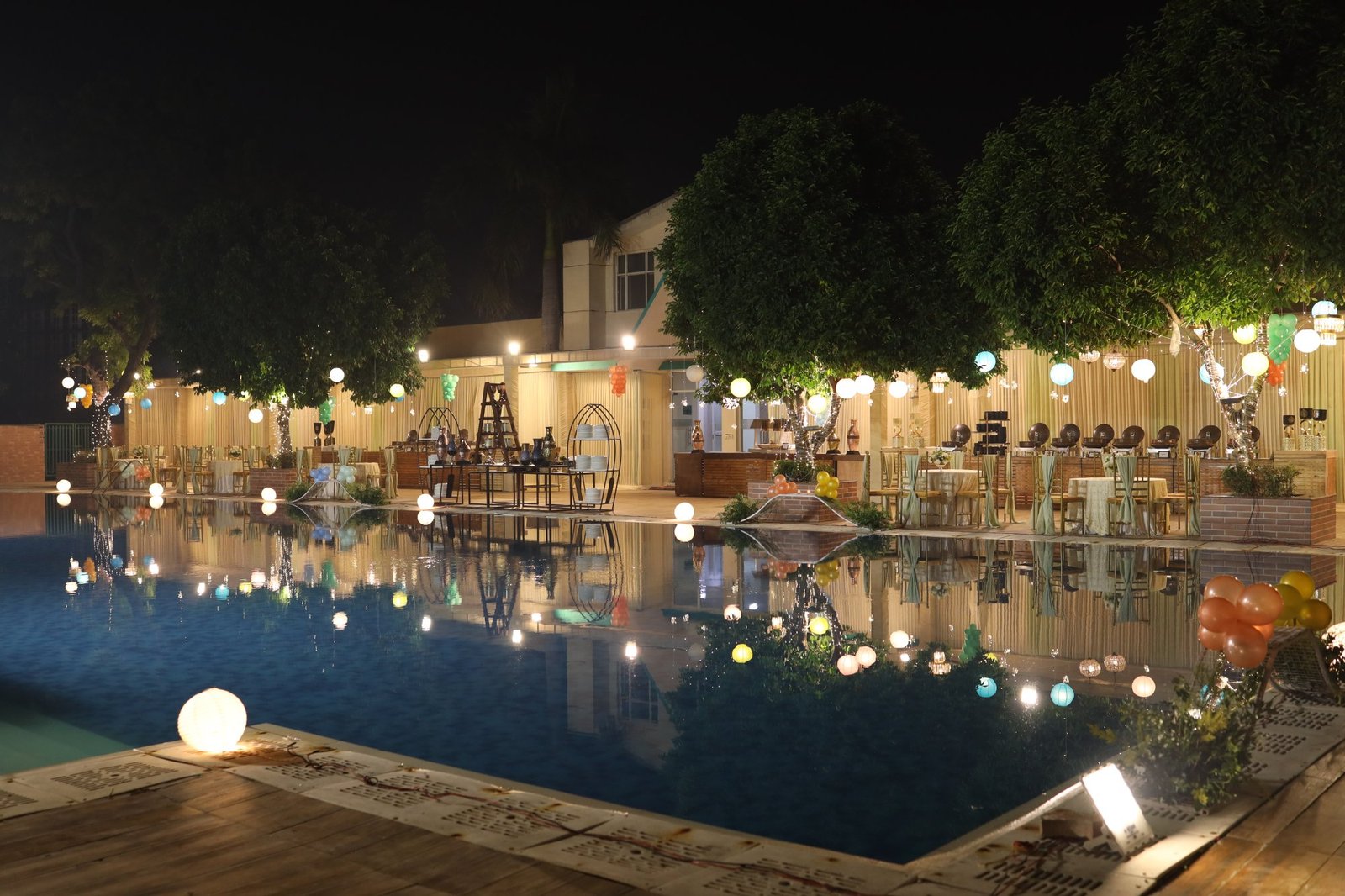 Birthday venue lit with festoon lights beside a pool in the evening