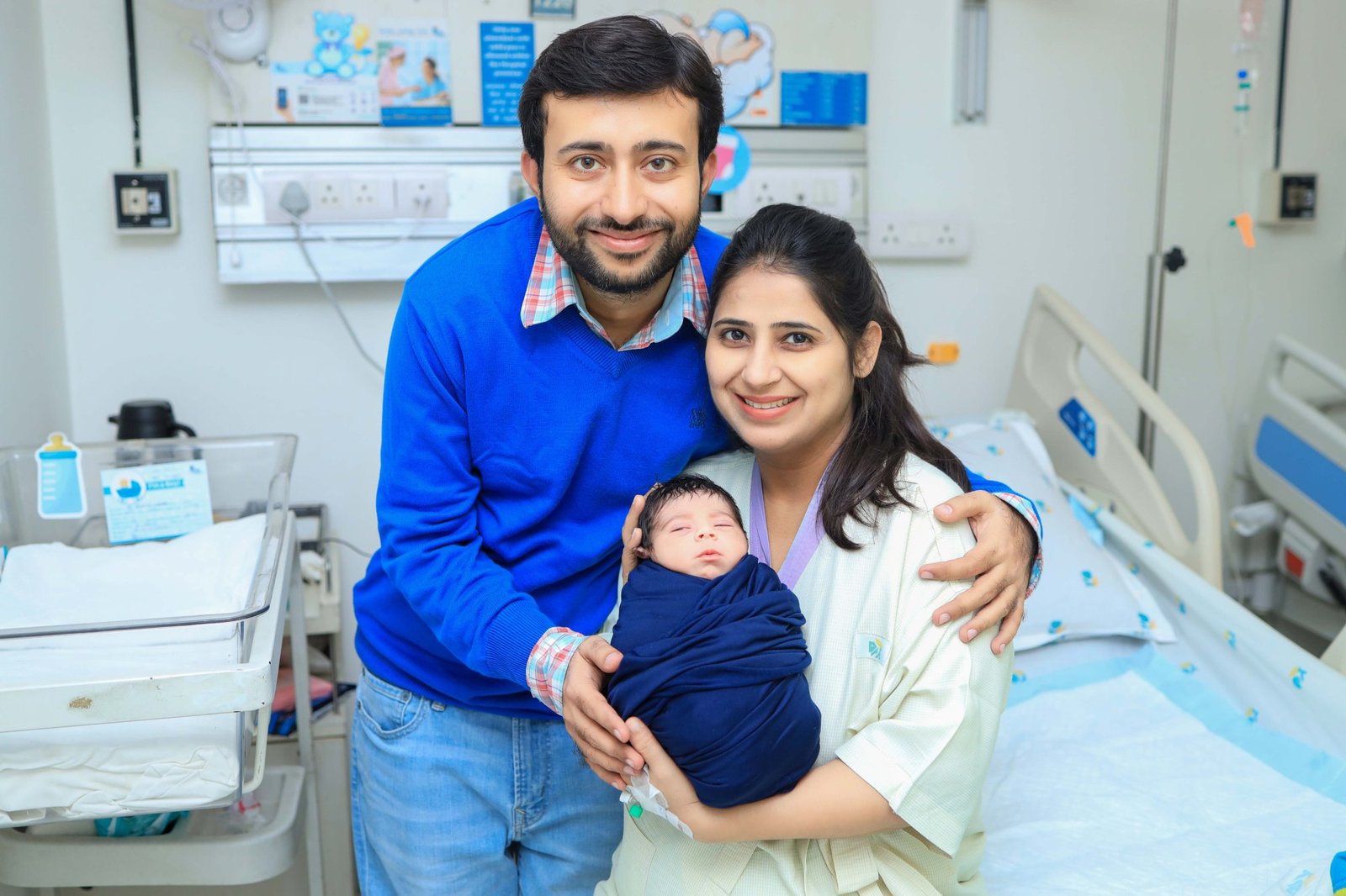 New parents with their newborn in the hospital room beside the cot