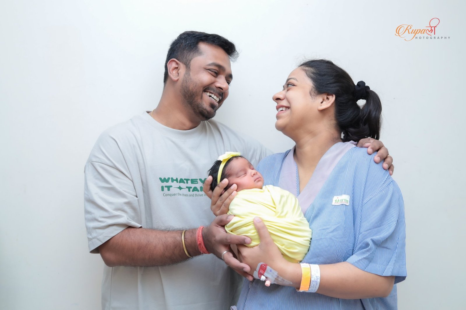 New parents standing together holding their newborn in the hospital