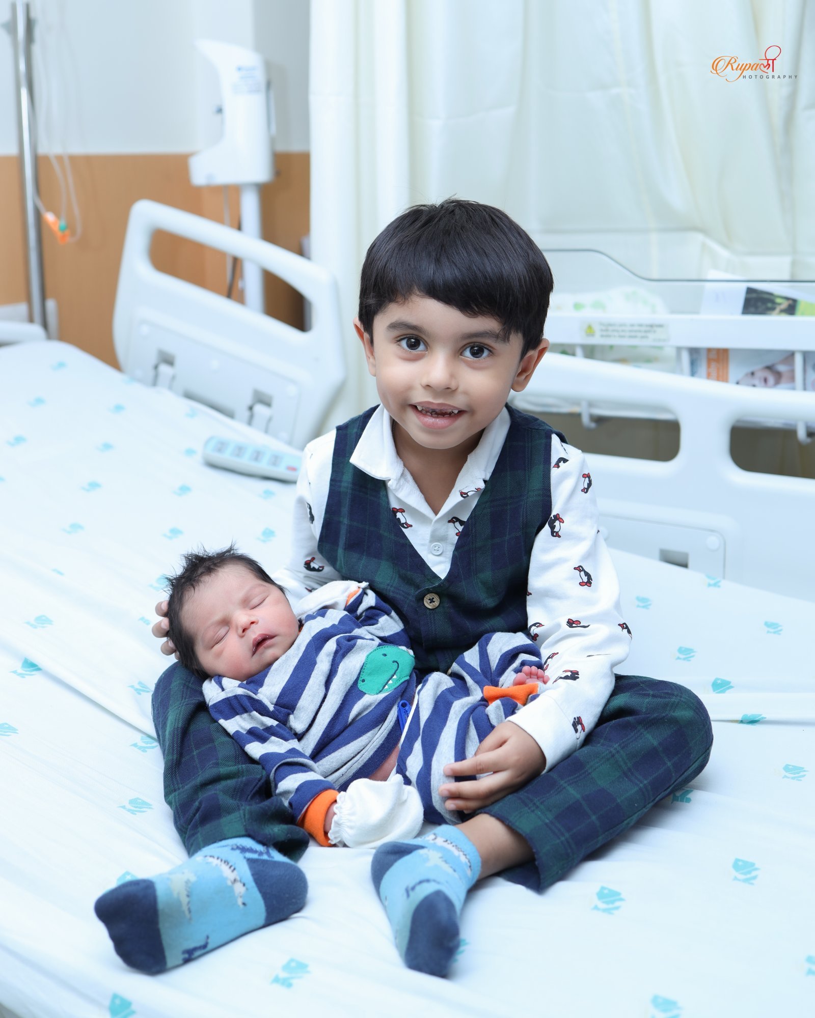 Older sibling sitting on a hospital bed meeting the newborn for the first time
