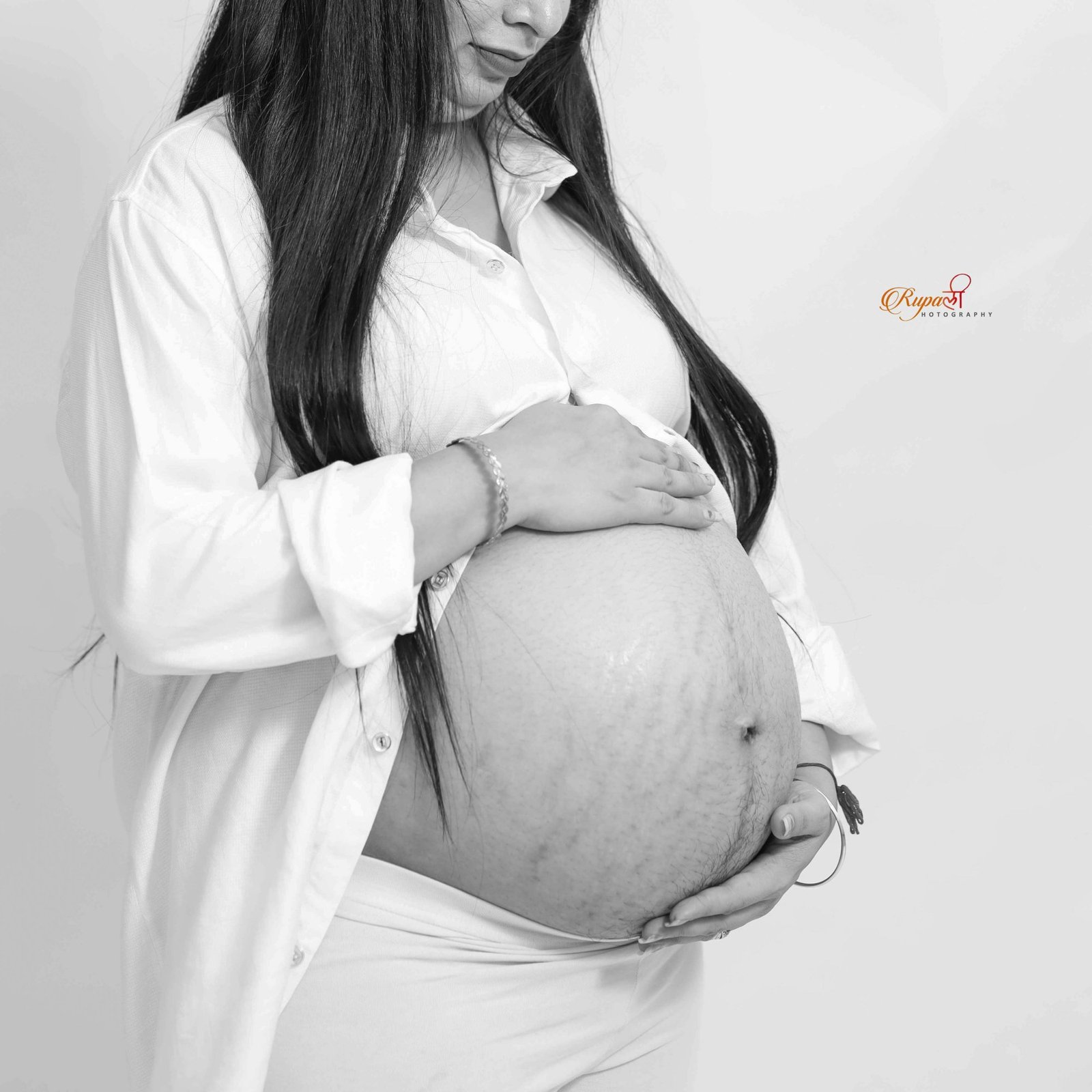 Black and white photograph of an expectant mother cradling her bump