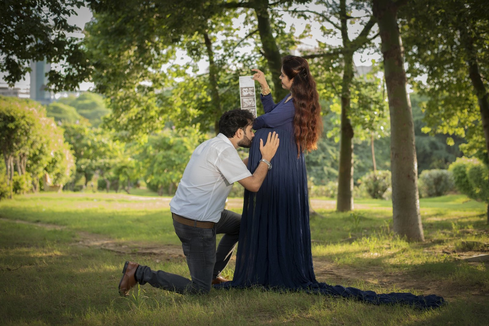 Partner kneeling to hold the bump during an outdoor park session