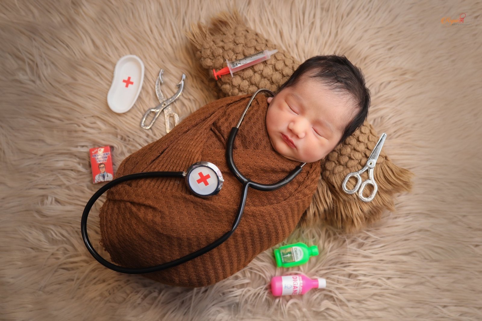 Newborn asleep in a themed setup with a toy stethoscope and props