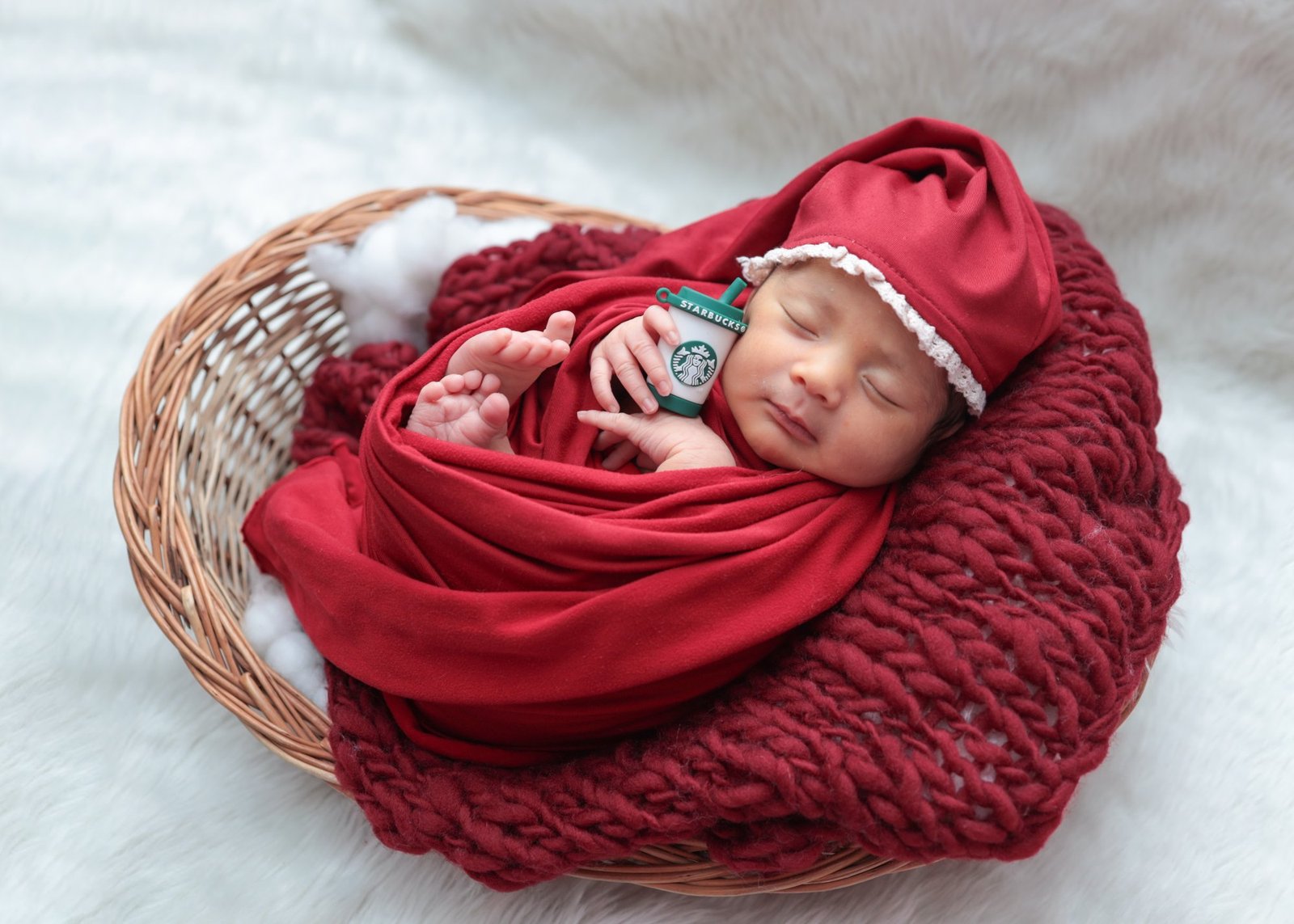 Newborn wrapped in red resting in a woven basket