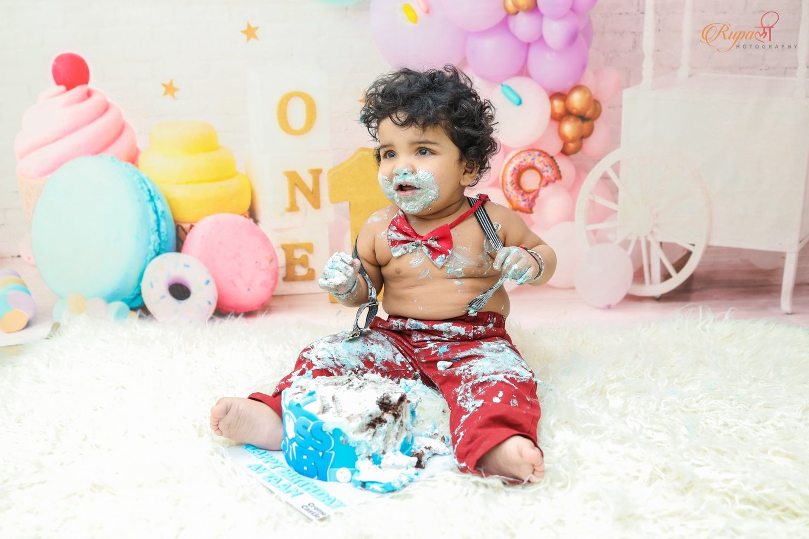 Baby exploring a cake with both hands on a pastel styled set