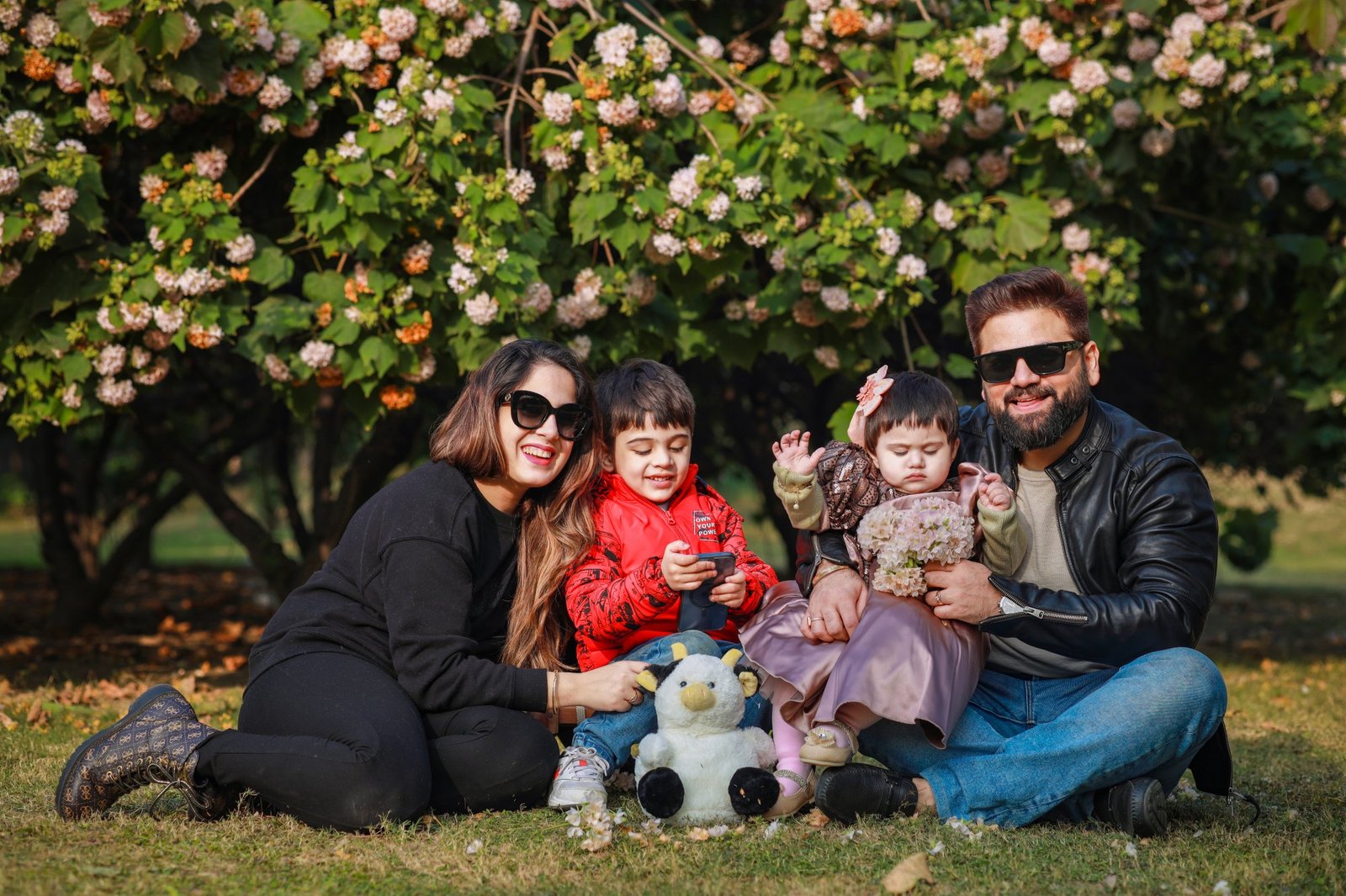 Family sitting together on the grass with their one year old at a park session