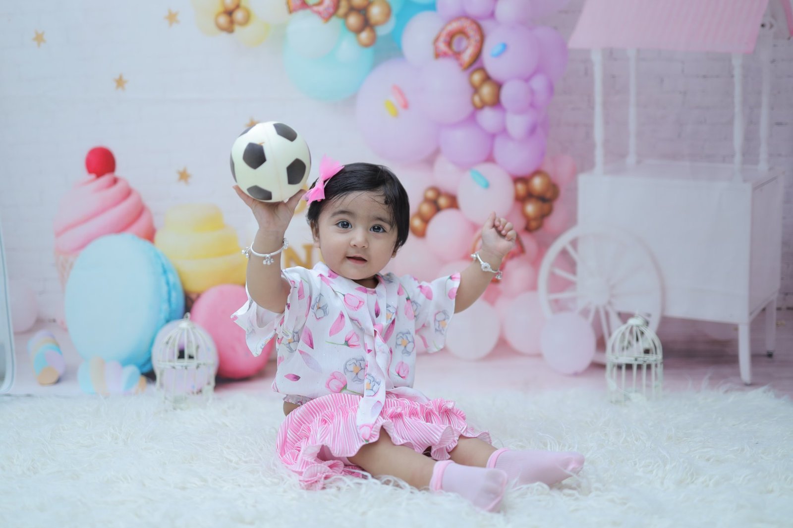 Baby on a pastel balloon set holding a football