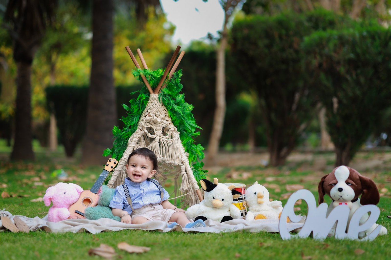 Outdoor teepee set with soft toys and a ONE sign on the grass