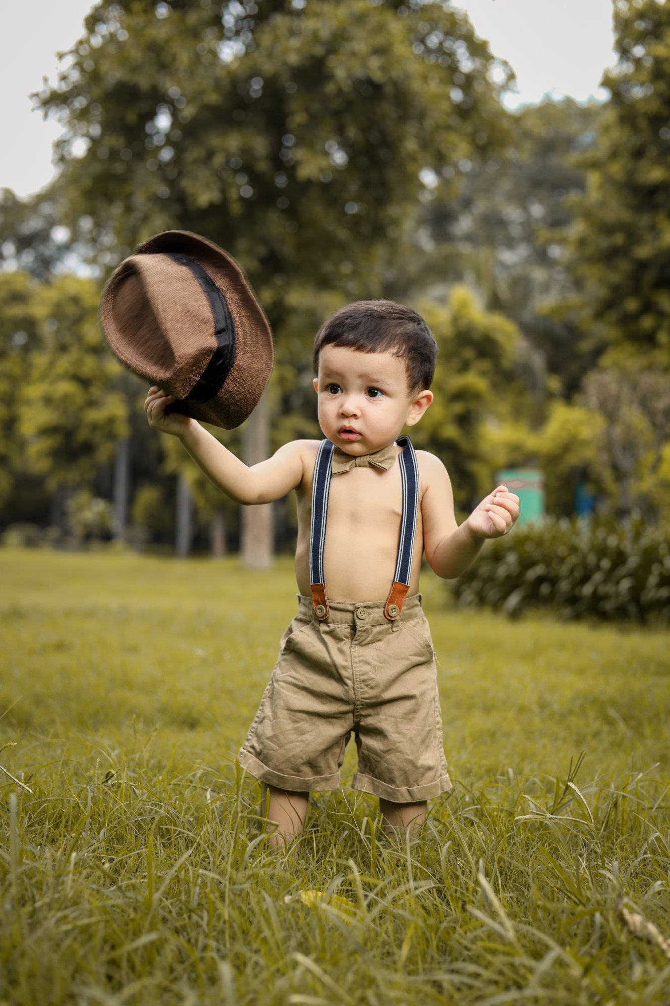 Toddler in braces lifting a hat during an outdoor park session