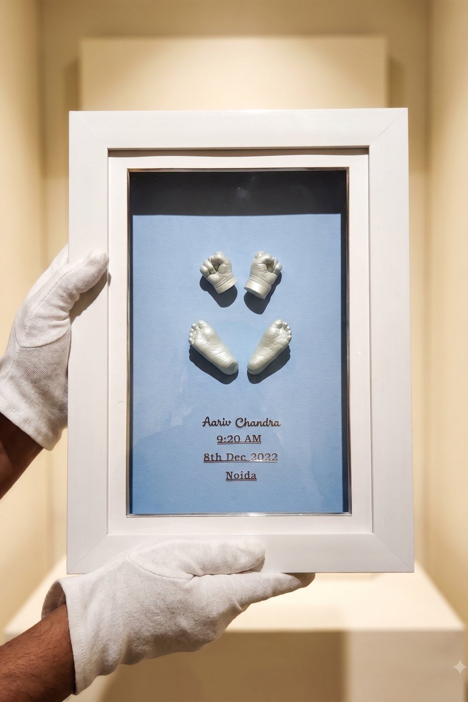 A pair of gold foot casts mounted in a white frame